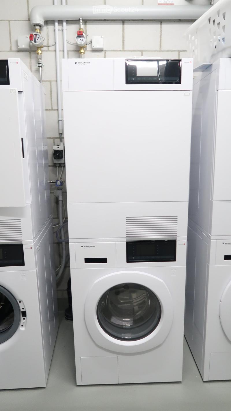 A clean, modern bathroom with a white washing machine and a dishwasher, both featuring sleek, contemporary designs.