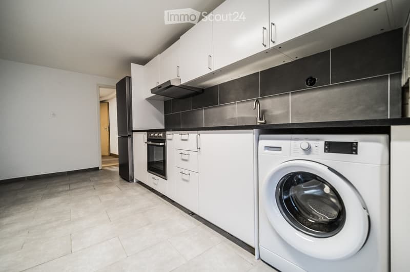 Modern kitchen with white cabinets, stainless steel appliances, and a tiled backsplash.