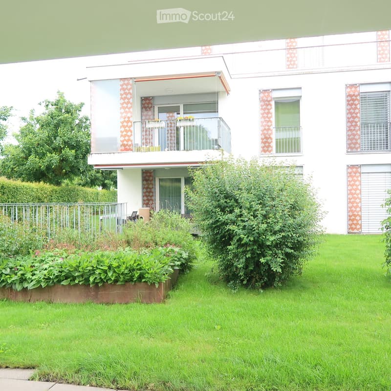 Two-story house with white exterior, balconies, and surrounding greenery.