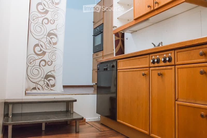 Modern kitchen with wooden cabinets, stainless steel appliances, and a decorative shower curtain in the background.