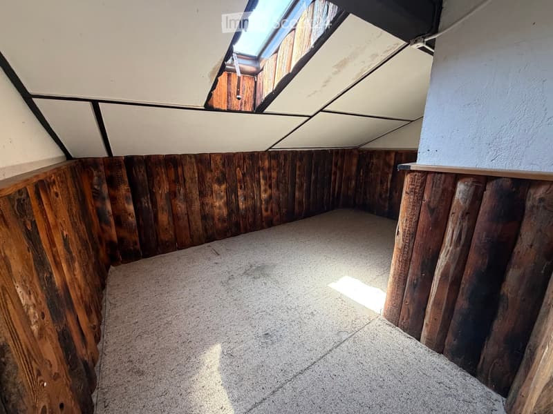 Empty room with wooden panel walls, concrete floor, and a skylight window at the top.