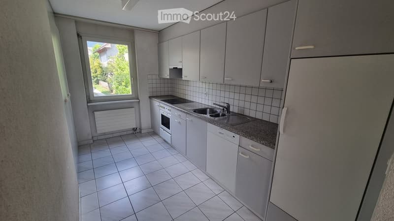 Modern kitchen with white cabinets, tiled floor, and granite countertop. Features a sink, faucet, oven, and dishwasher.