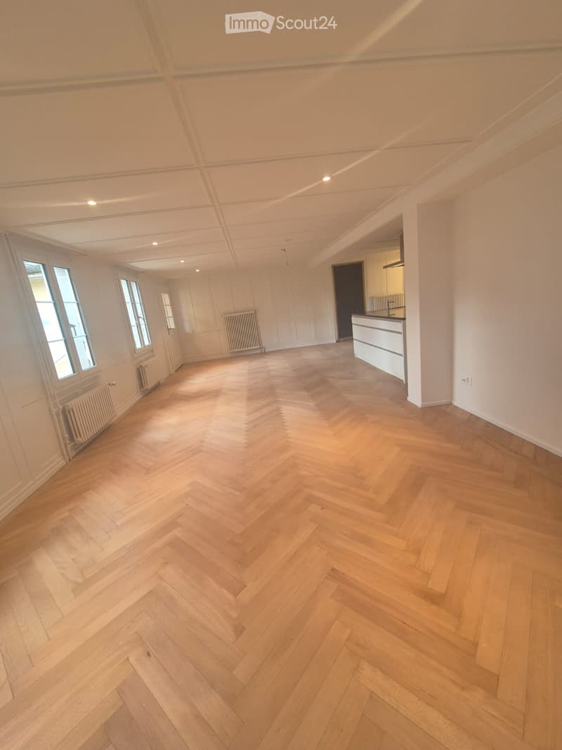 empty room, wooden parquet floor, white walls, white radiators, windows, kitchen area