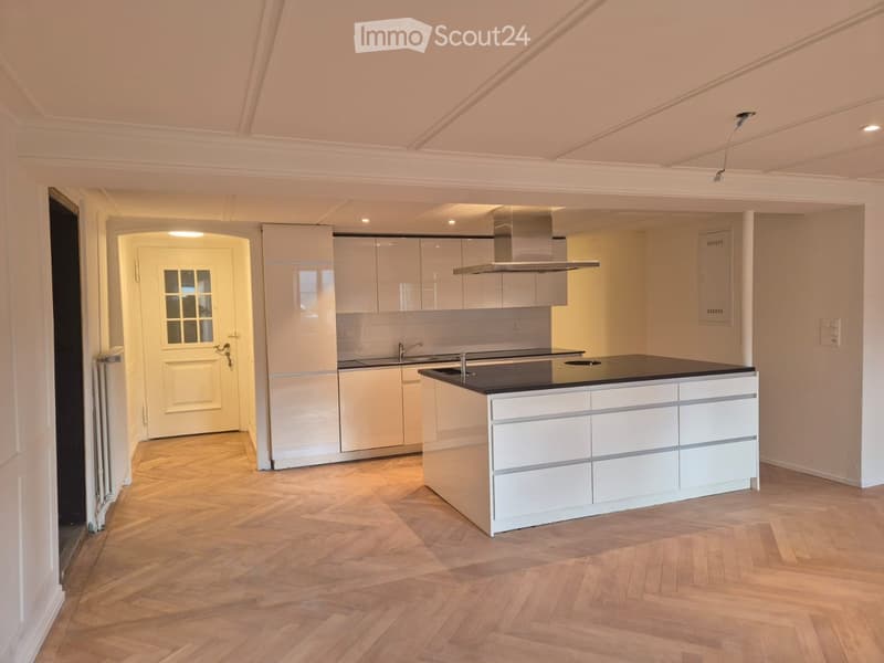 modern kitchen, white cabinets, black countertop, island, wooden floor, white walls, ceiling lights, exhaust hood, sink, faucet