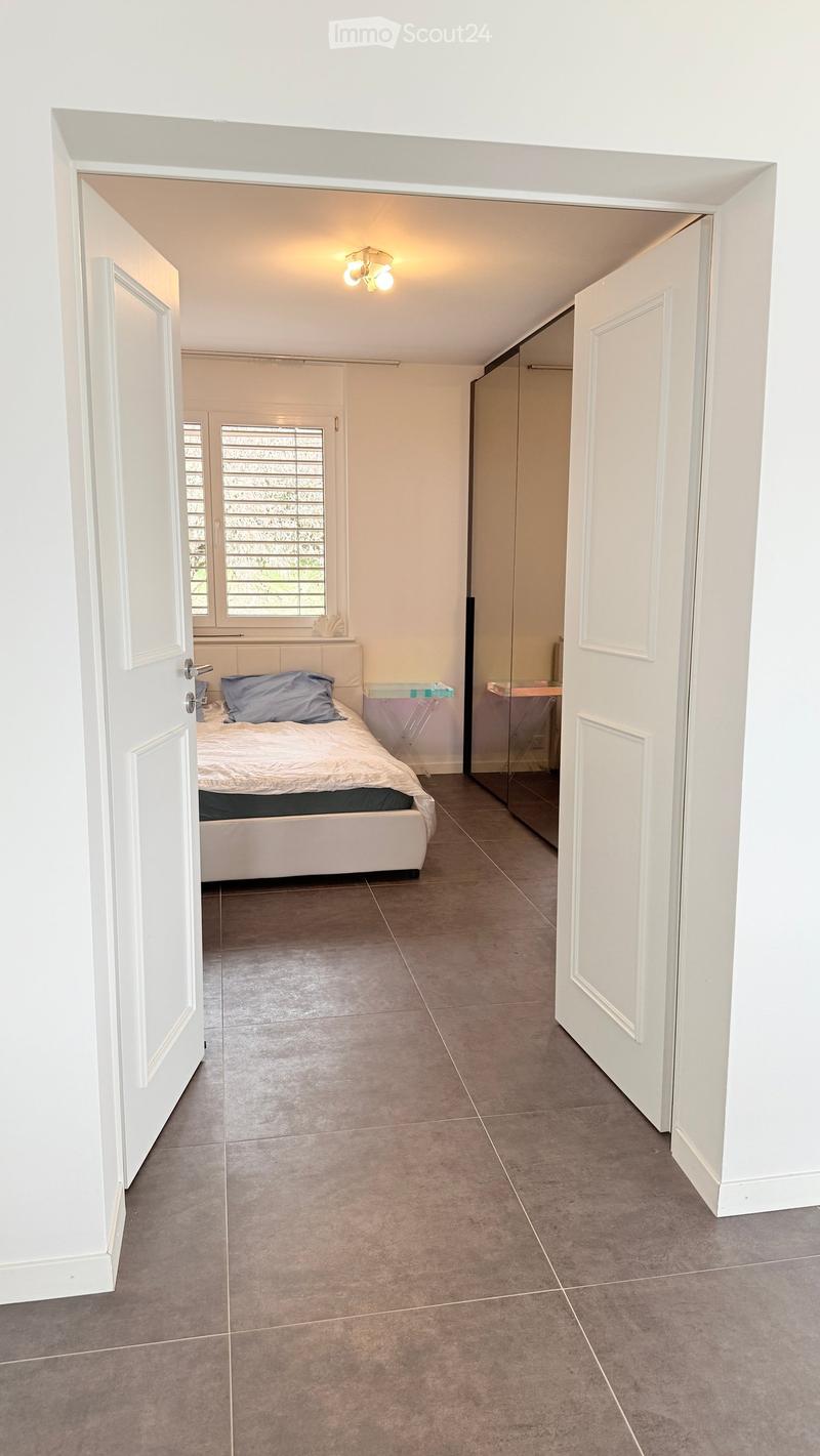 Hallway with tiled floor, white walls, and open doors leading to a bedroom and a closet area.