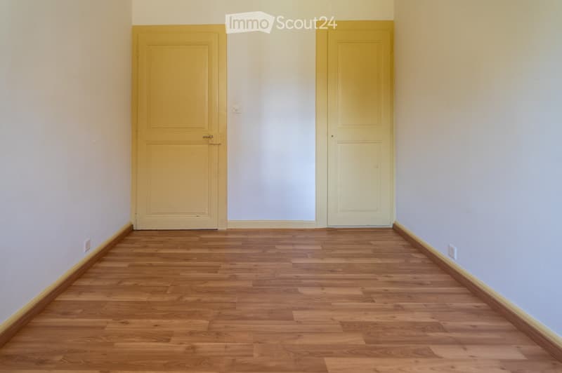 Empty room with wooden flooring and two yellow doors, no furniture or equipment present.