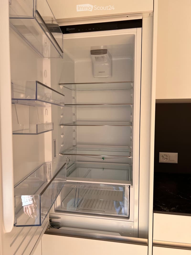 Open refrigerator with multiple glass shelves and compartments, featuring a clean and modern design.