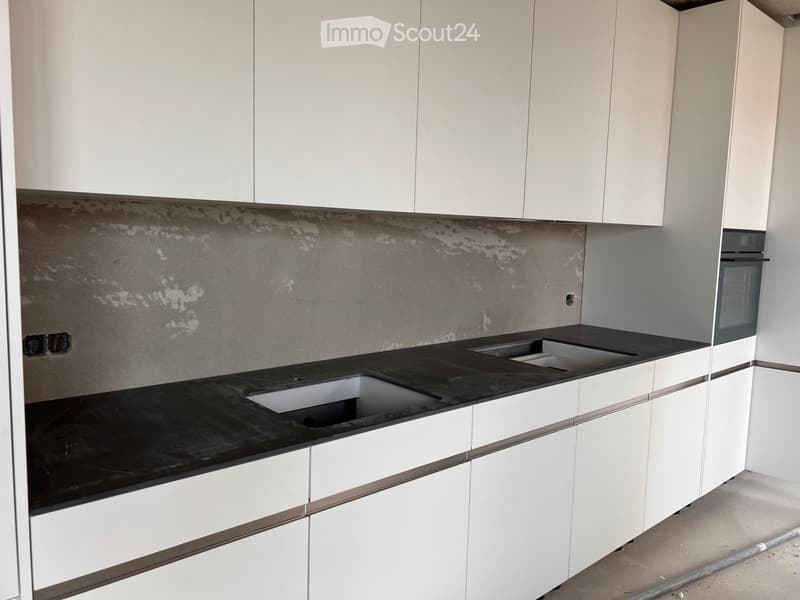 Modern kitchen with white cabinets, black countertop, and stainless steel sink and oven.