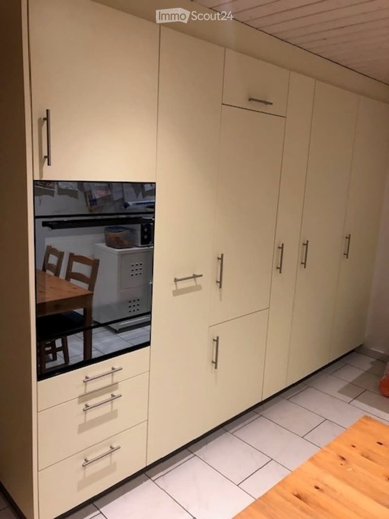 Modern kitchen with light-colored cabinets, a microwave, and a small dining area with a table and chairs.