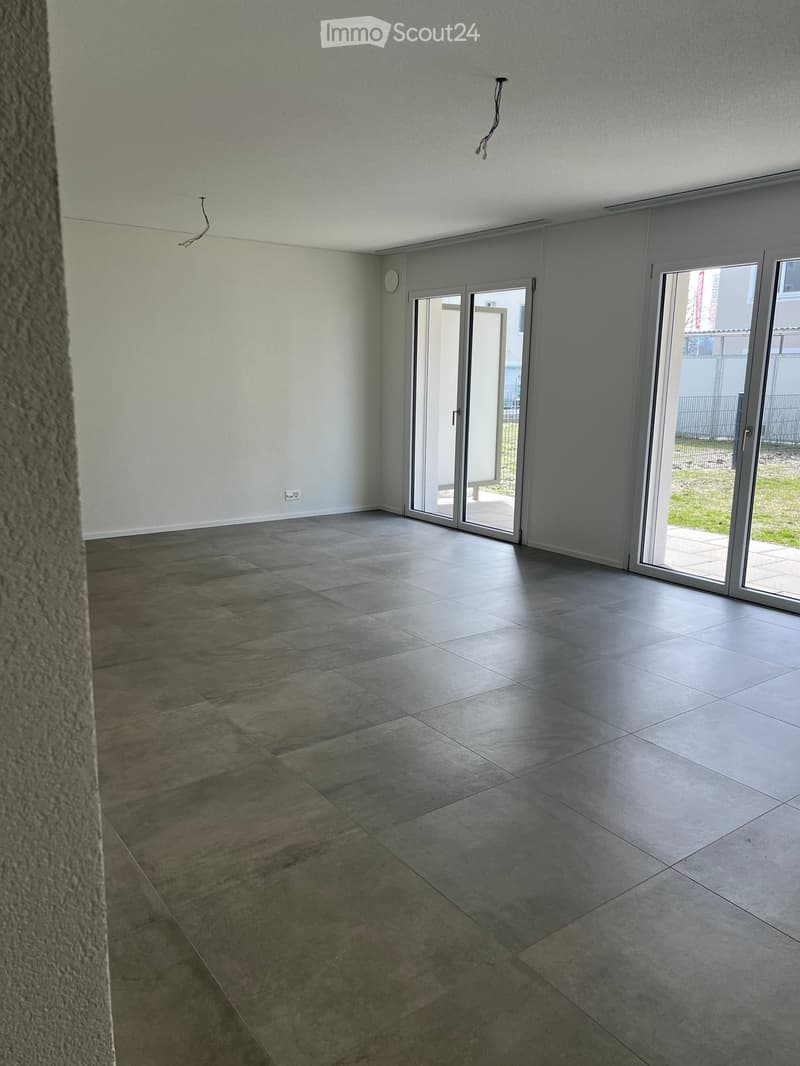 Empty room with tiled floor and large sliding glass doors leading to an outdoor area.