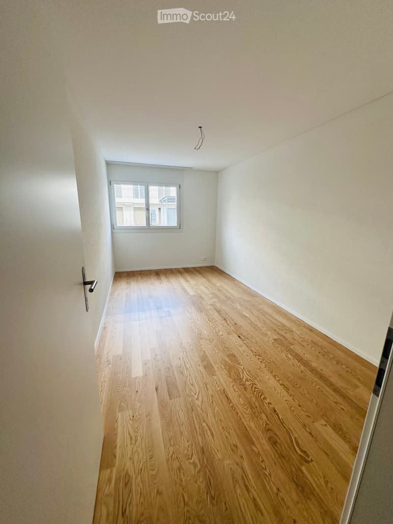 Empty room with light wooden flooring, white walls, and a single window with white frame. No furniture or equipment present.
