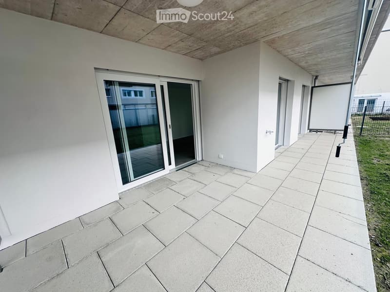 Modern covered balcony with large sliding glass doors, tiled floor, and white walls.