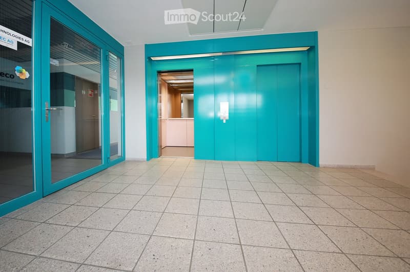 Empty hallway with tiled floor, teal-colored walls, and glass doors leading to adjacent spaces.