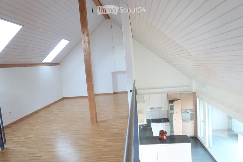 Bright, modern kitchen with white cabinets, wooden flooring, and large windows allowing natural light. Features a sink, oven, and countertop.