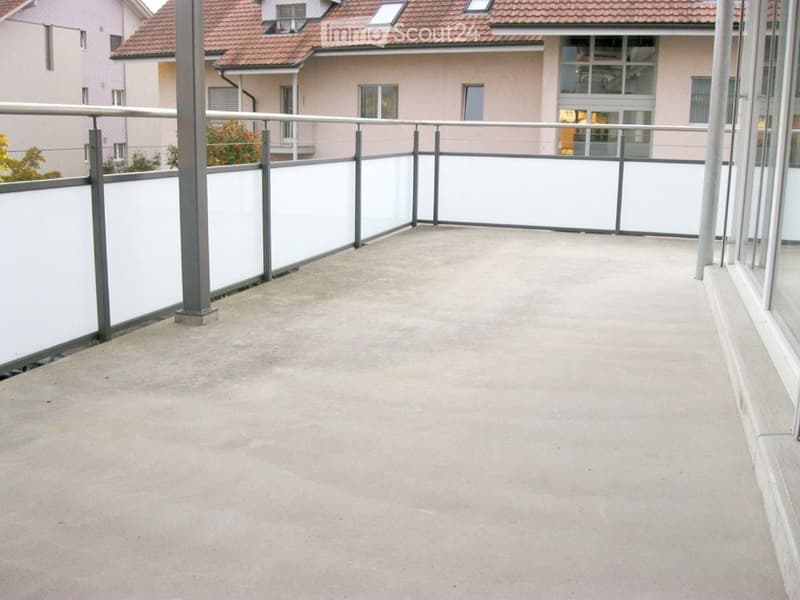 Empty balcony with white walls, metal railing, and concrete floor.