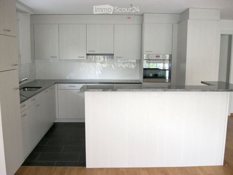 Modern kitchen with white cabinets, stainless steel appliances, granite countertops, and dark tiled floor.