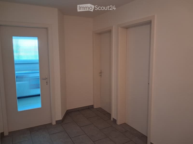 Empty room with tiled floor, light-colored walls, and two doors, one with a frosted glass window.