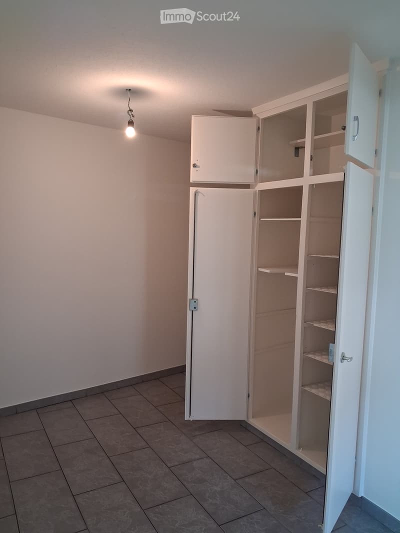 Empty room with tiled floor, white walls, and built-in white cabinets with open shelves.