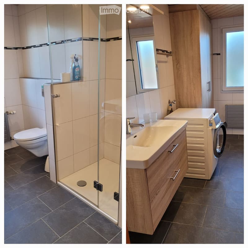 Modern bathroom with a glass-enclosed shower, toilet, sink, and washing machine. Features include wooden cabinets, a large mirror, and a window providing natural light.