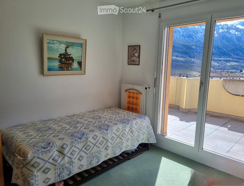 single bed, white walls, picture frame, sliding glass door, balcony, mountain view