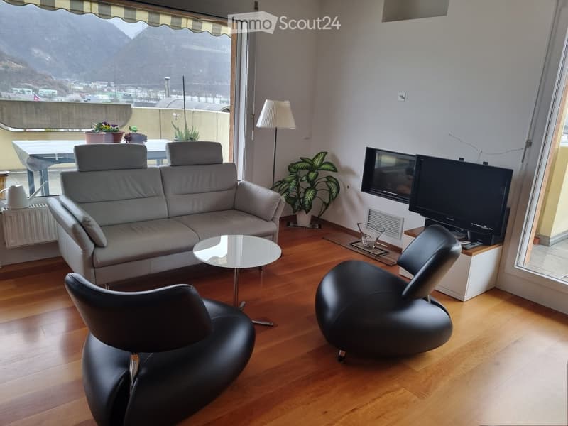living room with couch, two armchairs, table, television, plants, wooden floor