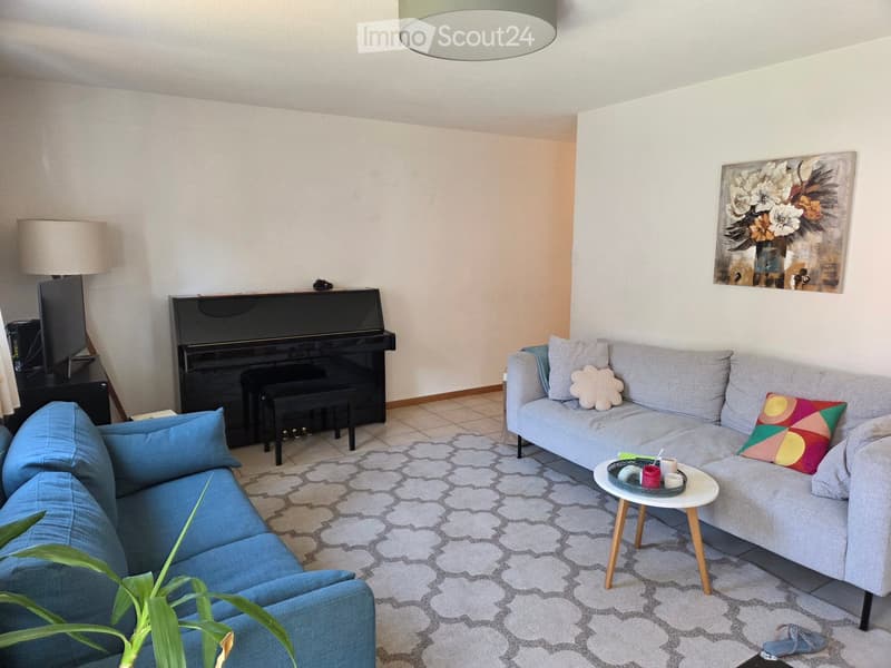 Modern living room with two sofas, a piano, a small table, and decorative pillows.