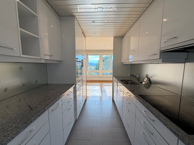 Modern kitchen with white cabinets, granite countertops, and stainless steel fixtures. Features a large window with a scenic view.