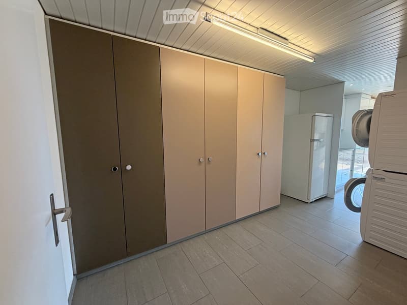 A well-lit, tiled room with a large wardrobe, a refrigerator, and a washing machine visible in the background.