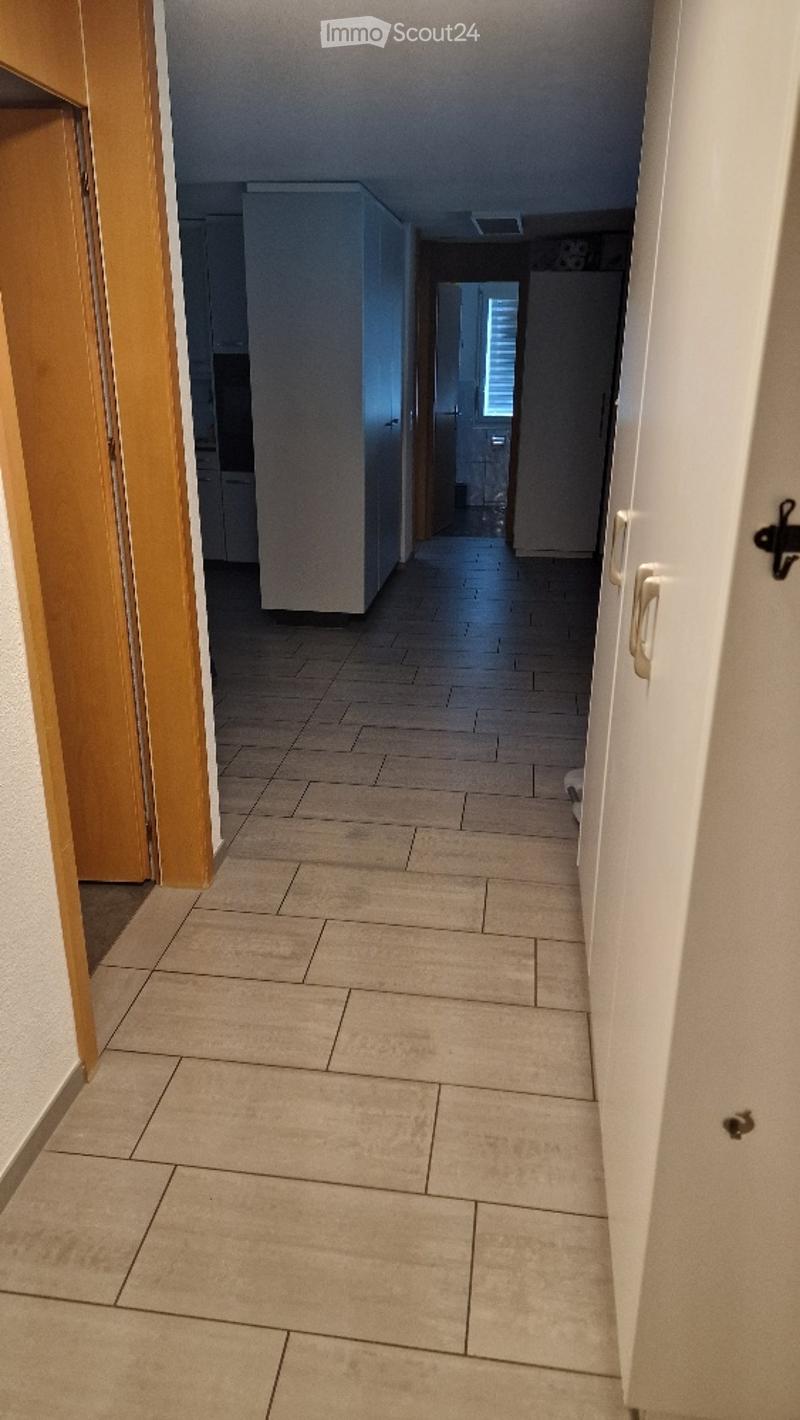 A clean, tiled hallway with white walls and wooden doors on either side, leading to other rooms.