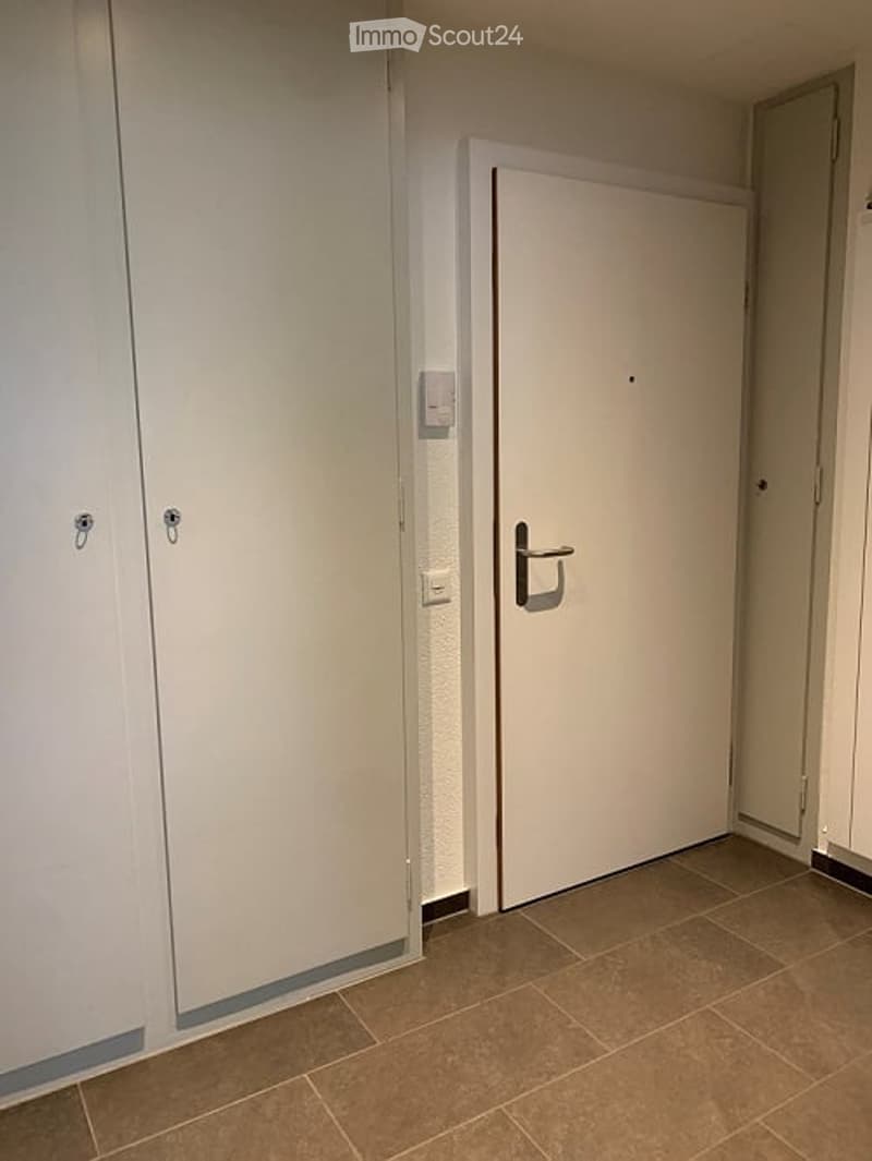 Empty room with white doors, tiled floor, power outlet on the wall
