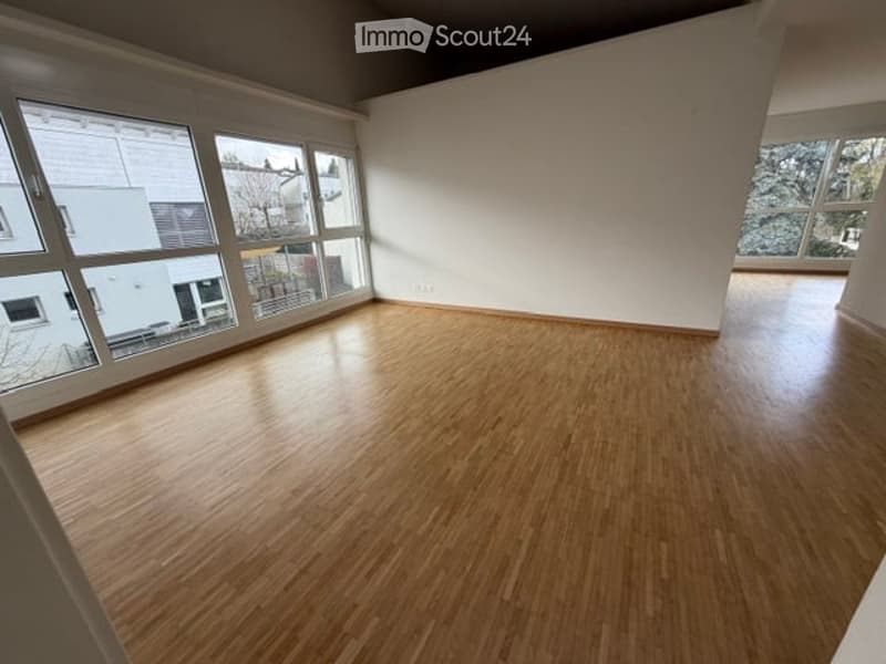 Empty room with wooden flooring and large windows, no furniture or equipment present.