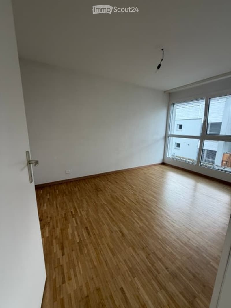 Empty room with wooden flooring and large windows, no furniture or equipment.