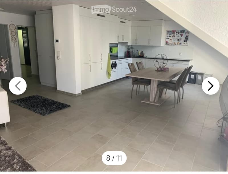 Modern kitchen and dining area with white cabinets, a wooden dining table, six chairs, and a tiled floor.