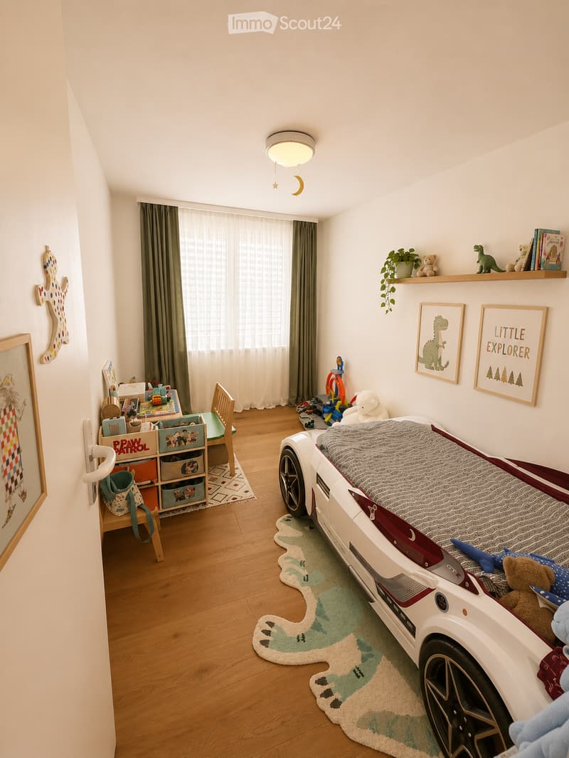 A well-lit children's bedroom with a car-shaped bed, a small chair, a storage unit, and various toys and decorations.