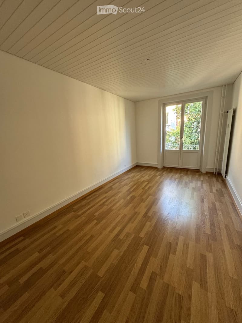 Empty room with wooden flooring, white walls, and a sliding glass door leading to an outdoor area.