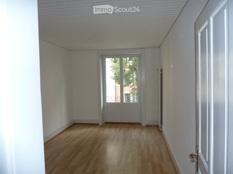 Empty room with wooden flooring, white walls, and a door leading to a balcony or outdoor area.