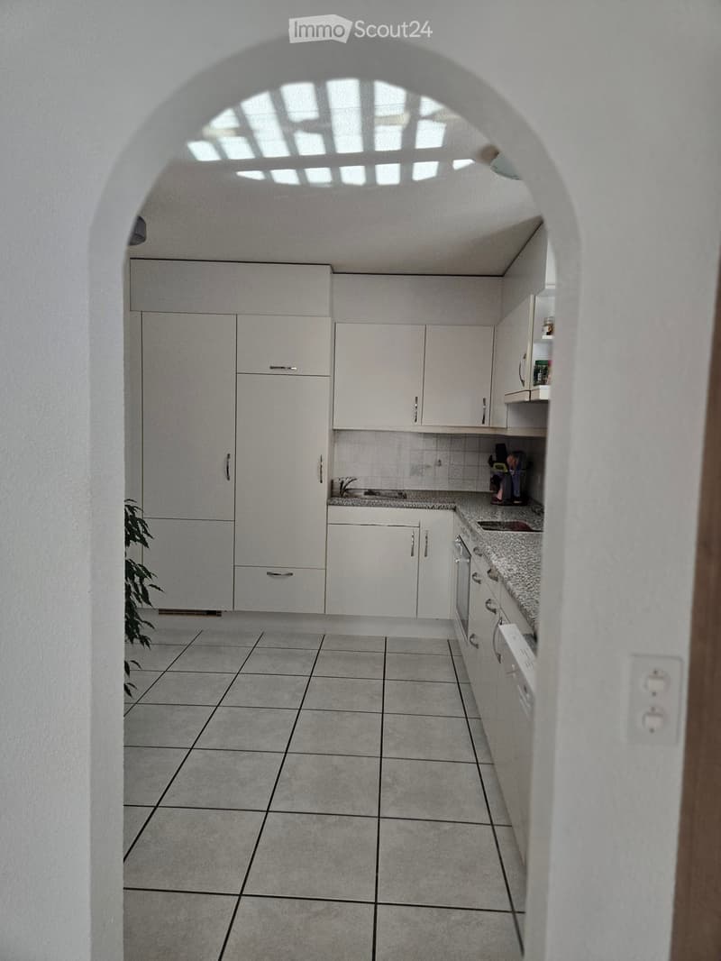Modern kitchen with white cabinets, granite countertop, tiled floor, and built-in appliances.