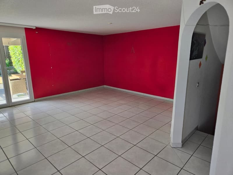 Empty room with red walls, tiled floor, and large sliding glass door leading to outdoor area.