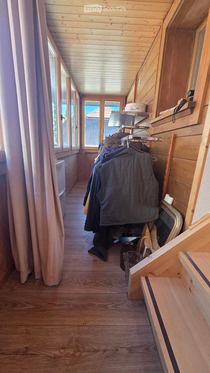 Wooden hallway with large windows, coat rack, and staircase leading upwards.