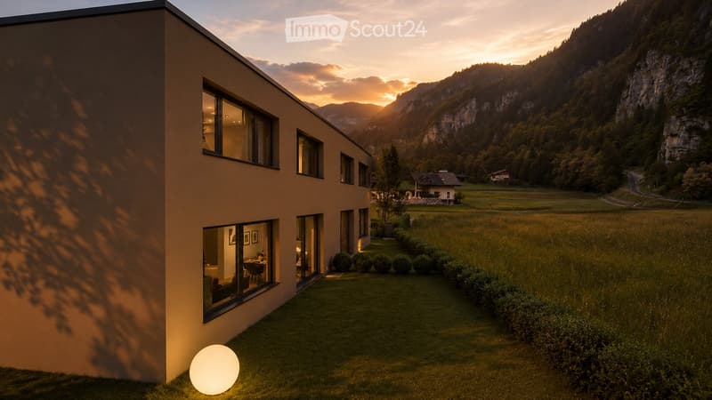 Modern two-story house with large windows, surrounded by a well-maintained lawn and bushes, with a scenic mountain view in the background.