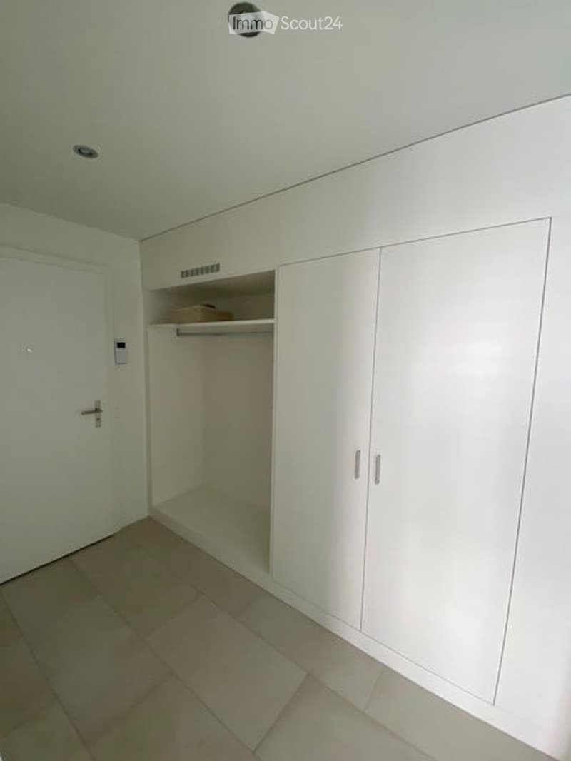 Empty room with white built-in wardrobes, tiled floor, and white walls. No furniture or personal items present.