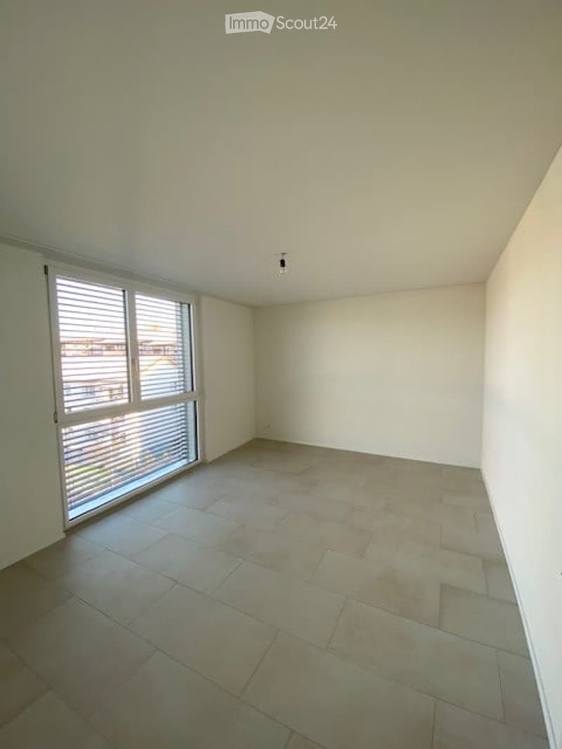 Empty room with tiled floor, white walls, and large window with blinds.