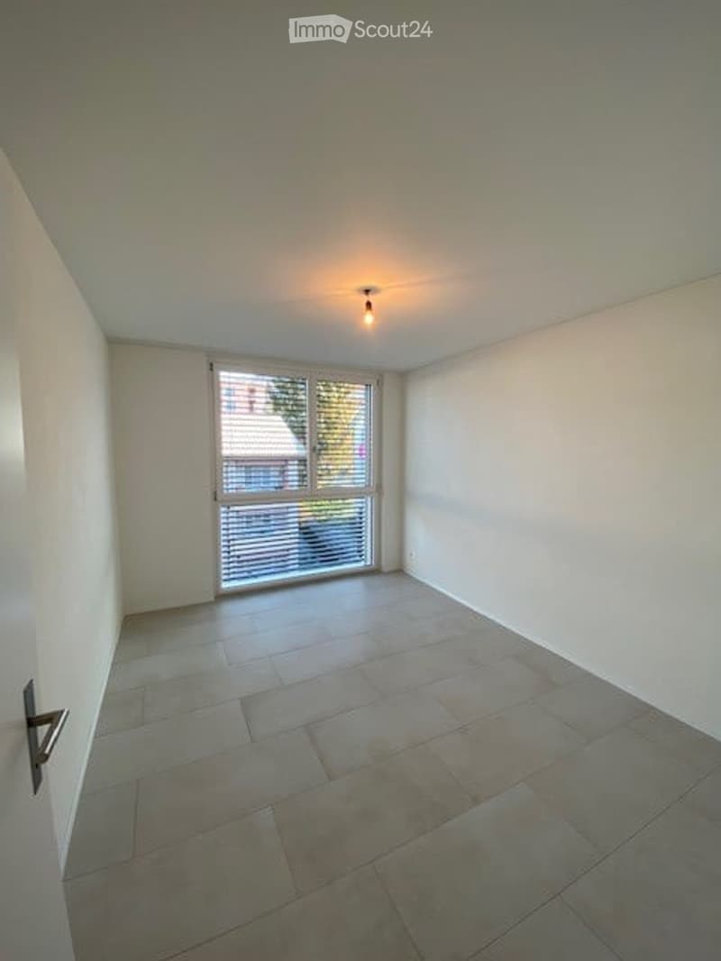 Empty room with tiled floor, white walls, and a large window with blinds. No furniture or equipment present.