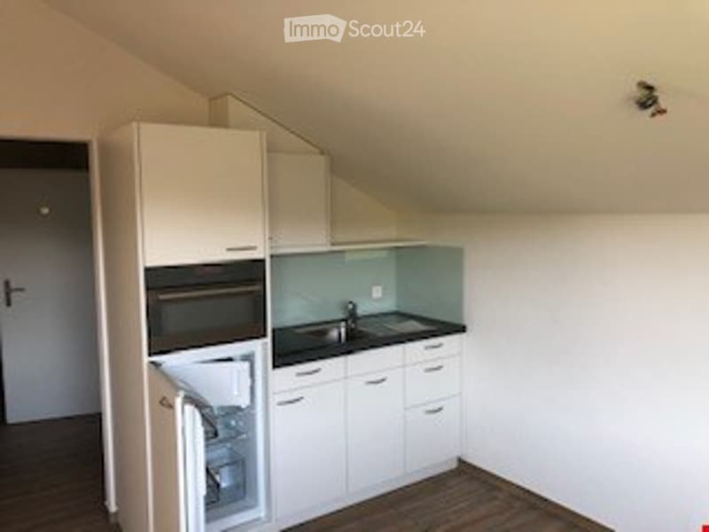 Modern kitchen with white cabinets, stainless steel appliances, and a black countertop.