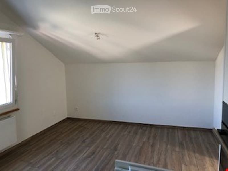 Completely empty room with wooden flooring, white walls, and a single window. No furniture or equipment present.