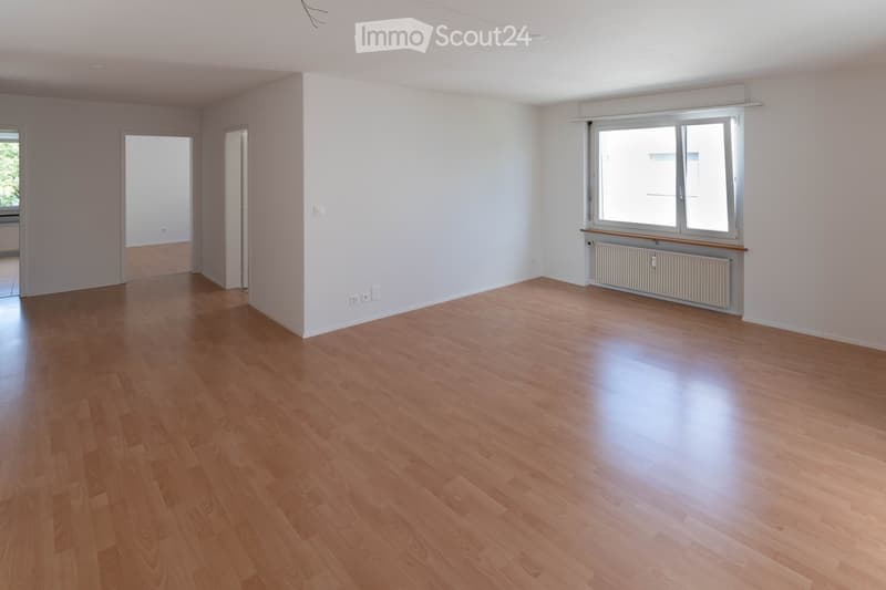 Empty room with wooden flooring, white walls, and large windows with radiators underneath. No furniture or equipment present.