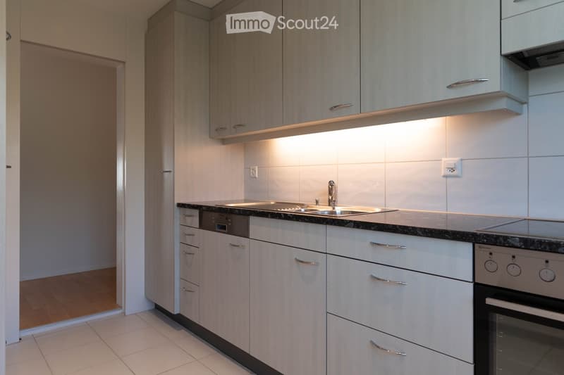 Modern kitchen with white cabinets, granite countertop, stainless steel sink, and built-in appliances including an oven and dishwasher.