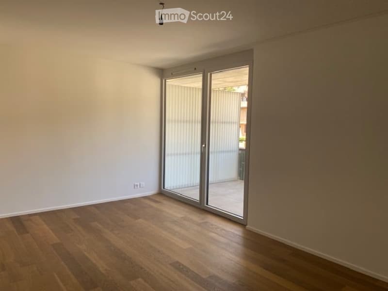 Empty room with wooden flooring, large sliding glass doors, and white walls.