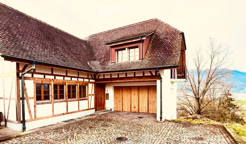 Timber-framed house, red tiles, white and wooden exterior, wooden garage door, several windows