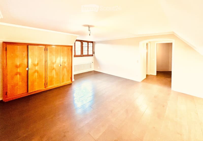 Empty room with hardwood floors, white walls, wooden closet, small window, and a radiator on the wall